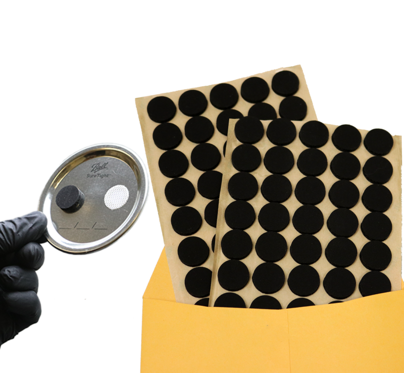 Black filter patches on yellow envelope with jar lid held by a gloved hand