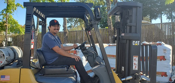 Carlos Camacho on a forklift at Left Coast Wholesale in front of Royal Gold soil pallets