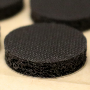 A close-up of a sheet of Microppose self-healing injection ports, showcasing the textured surface and the adhesive backing for application to cultivation jars.